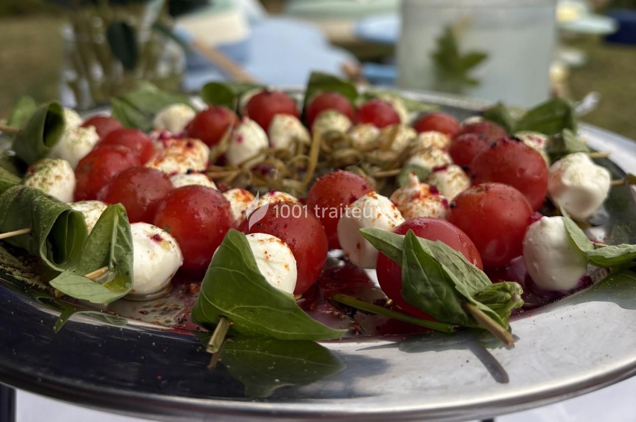 Brochettes de tomates cerises, mozzarella et feuilles de basilic, présentées sur un plateau en métal.