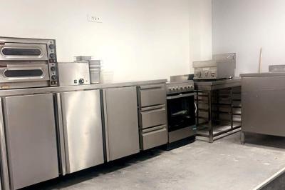 Cuisine professionnelle avec équipements en inox, comprenant fours, plaques de cuisson, plans de travail et rangements.