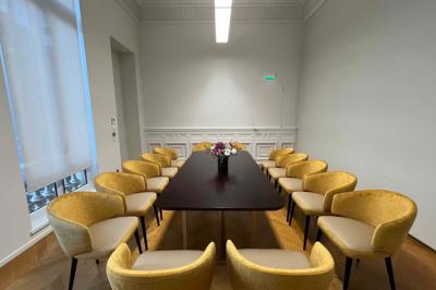 Un groupe de mannequins en tenues élégantes défile sur une scène, observé par un public dans une salle lumineuse.