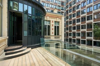 Un groupe de mannequins en tenues élégantes défile sur une scène, observé par un public dans une salle lumineuse.