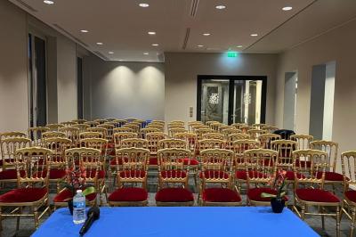 Un groupe de mannequins en tenues élégantes défile sur une scène, observé par un public dans une salle lumineuse.
