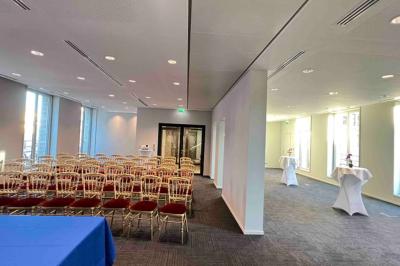 Un groupe de mannequins en tenues élégantes défile sur une scène, observé par un public dans une salle lumineuse.