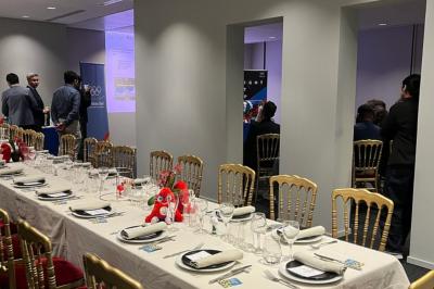 Un groupe de mannequins en tenues élégantes défile sur une scène, observé par un public dans une salle lumineuse.