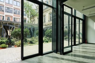 Un groupe de mannequins en tenues élégantes défile sur une scène, observé par un public dans une salle lumineuse.