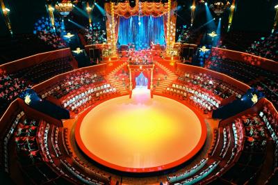 Salle vide avec éclairage rouge, rideaux en arrière-plan, scène surélevée et comptoirs alignés sur les côtés.