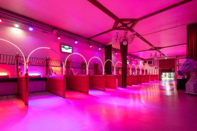 Salle vide avec éclairage rouge, rideaux en arrière-plan, scène surélevée et comptoirs alignés sur les côtés.