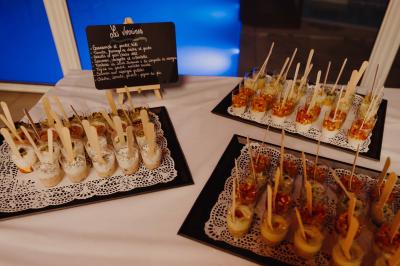 Terrasse en bois avec table dressée, chaises noires, barbecue et vue sur des toits de maisons, sous une pergola rouge.