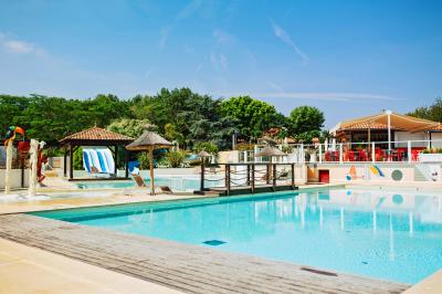 Terrasse en bois avec table dressée, chaises noires, barbecue et vue sur des toits de maisons, sous une pergola rouge.