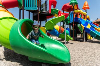 Terrasse en bois avec table dressée, chaises noires, barbecue et vue sur des maisons à colombages rouges et blanches.