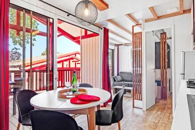 Terrasse en bois avec table dressée, chaises noires, barbecue et vue sur des maisons à colombages rouges et blanches.
