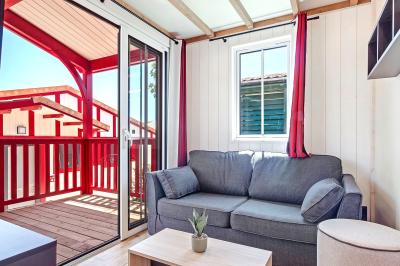 Terrasse en bois avec table dressée, chaises noires, barbecue et vue sur des maisons à colombages rouges et blanches.