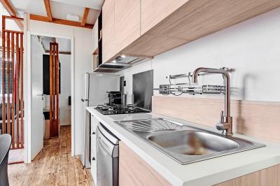 Terrasse en bois avec table dressée, chaises noires, barbecue et vue sur des maisons à colombages rouges et blanches.
