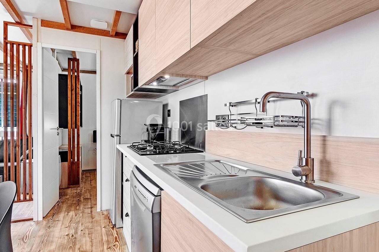 Cuisine moderne avec plan de travail en bois clair, évier en inox, plaques de cuisson et rangements intégrés.