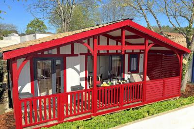 Terrasse en bois avec table dressée, chaises noires, barbecue et vue sur des maisons à colombages rouges et blanches.