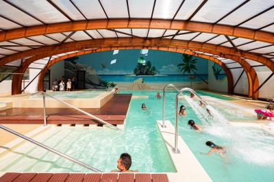Terrasse en bois avec table dressée, chaises noires, barbecue et vue sur des maisons à colombages rouges et blanches.