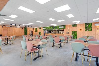 Terrasse en bois avec table dressée, chaises noires, barbecue et vue sur des maisons à colombages rouges et blanches.