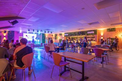 Terrasse en bois avec table dressée, chaises noires, barbecue et vue sur des maisons à colombages rouges et blanches.
