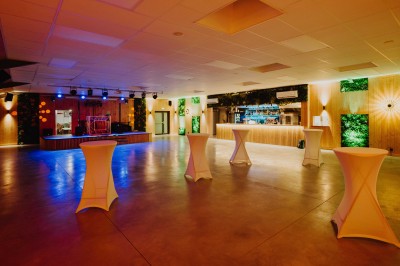 Terrasse en bois avec table dressée, chaises noires, barbecue et vue sur des maisons à colombages rouges et blanches.