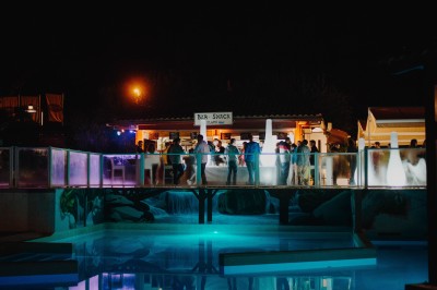Terrasse en bois avec table dressée, chaises noires, barbecue et vue sur des maisons à colombages rouges et blanches.