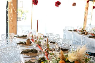 Terrasse en bois avec table dressée, chaises noires, barbecue et vue sur des maisons à colombages rouges et blanches.