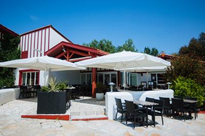 Terrasse en bois avec table dressée, chaises noires, barbecue et vue sur des maisons à colombages rouges et blanches.