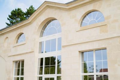 Cour pavée avec un bâtiment en briques rouges et toit en ardoise, entouré de végétation sous un ciel bleu.