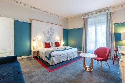 Terrasse extérieure avec tables, chaises et parasols devant un bâtiment en pierre sous une verrière.