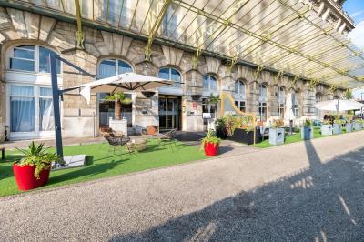 Terrasse extérieure avec tables, chaises et parasols devant un bâtiment en pierre sous une verrière.