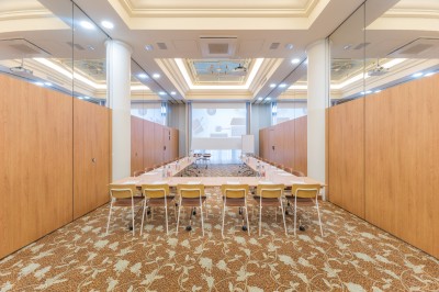 Terrasse extérieure avec tables, chaises et parasols devant un bâtiment en pierre sous une verrière.