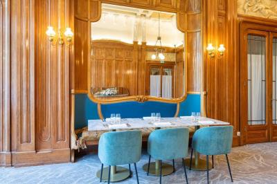 Chambre d'hôtel avec lit double, mur bleu, fauteuil rouge, table basse et décoration murale en forme de main.