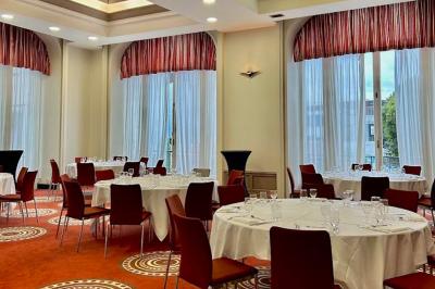 Chambre d'hôtel avec lit double, mur bleu, fauteuil rouge, table basse et décoration murale en forme de main.