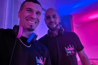 Table de mixage DJ avec platines, boutons lumineux, écran tactile et microphone sur une scène éclairée.