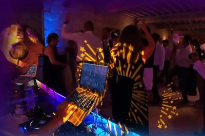 Table de mixage DJ avec platines, boutons lumineux, écran tactile et microphone sur une scène éclairée.