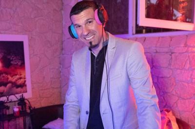 Table de mixage DJ avec platines, boutons lumineux, écran tactile et microphone sur une scène éclairée.