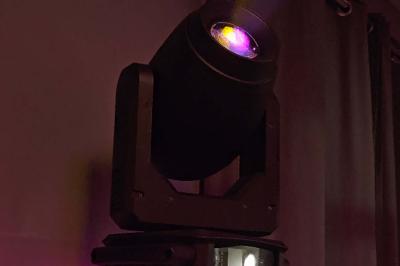 Table de mixage DJ avec platines, boutons lumineux, écran tactile et microphone sur une scène éclairée.