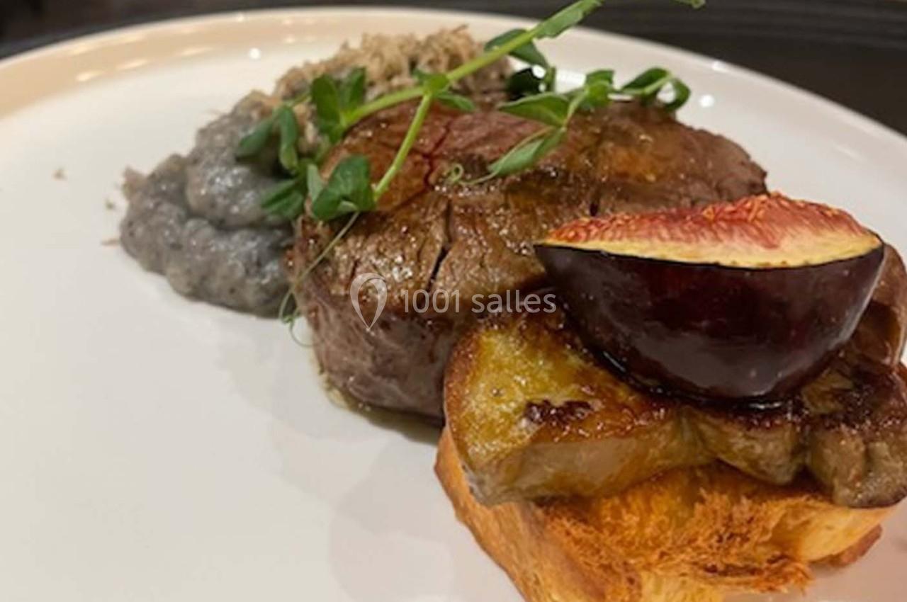 Plat composé d'un filet de viande, foie gras sur pain grillé, figue rôtie et purée garnie de pousses vertes.