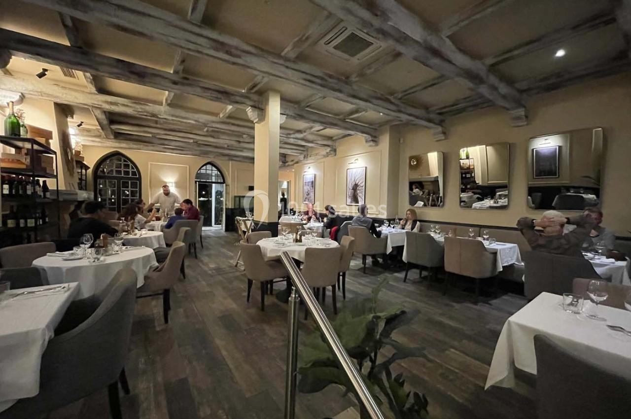 Salle de restaurant élégante avec tables dressées, clients attablés et éclairage tamisé.