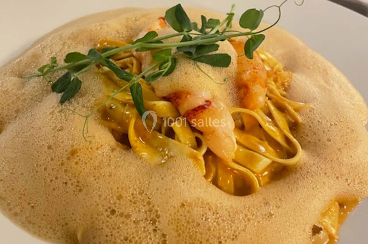 Assiette de pâtes fraîches aux crevettes, nappées d'une émulsion légère et garnies de pousses vertes.