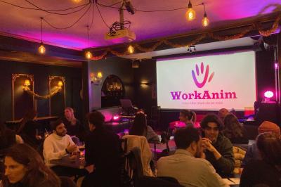 Des personnes rient et participent à une activité conviviale dans un espace chaleureux avec une ambiance lumineuse colorée.