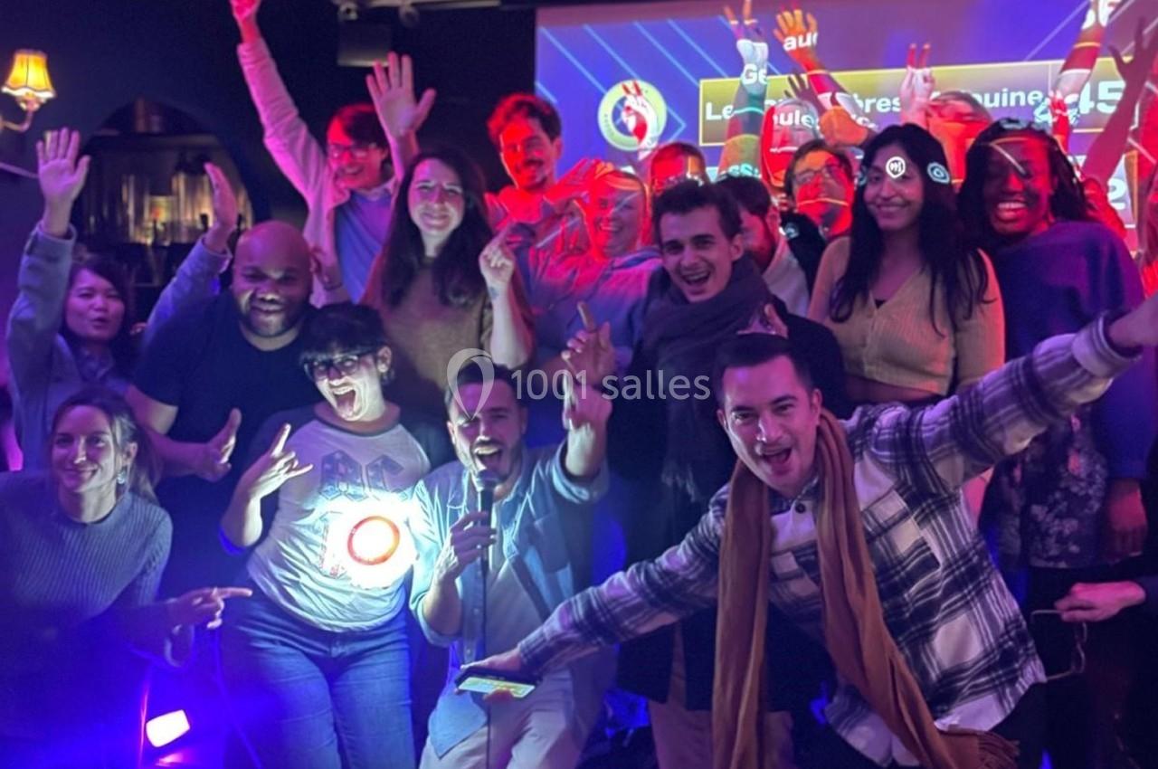 Un groupe de personnes souriantes pose joyeusement dans un environnement festif avec des lumières colorées.