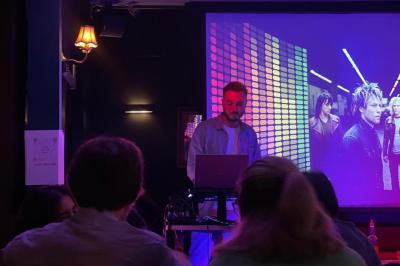 Salle animée avec des personnes assises à des tables, éclairage tamisé et écran affichant ’WorkAnim’.