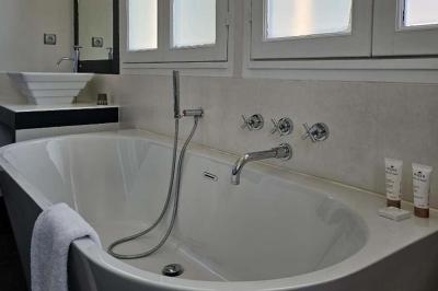 Baignoire blanche avec robinetterie moderne, serviette accrochée et produits de soin posés sur le rebord.