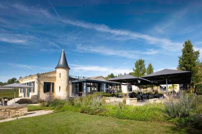 Salle de bain avec baignoire blanche, robinetterie moderne, vasque en arrière-plan et produits de toilette posés.