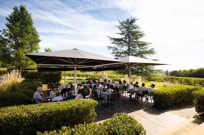 Salle de bain avec baignoire blanche, robinetterie moderne, vasque en arrière-plan et produits de toilette posés.