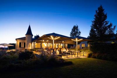 Salle de bain avec baignoire blanche, robinetterie moderne, vasque en arrière-plan et produits de toilette posés.