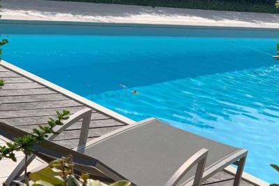 Salle de bain avec baignoire blanche, robinetterie moderne, vasque en arrière-plan et produits de toilette posés.