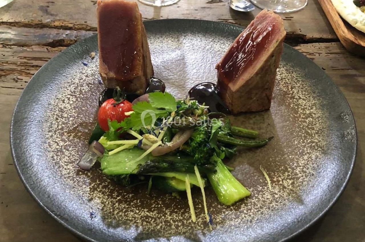 Assiette avec deux morceaux de viande grillée, légumes verts sautés, tomate cerise et herbes fraîches.