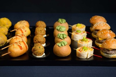Plateau de bouchées variées comprenant mini-burgers, wraps, brochettes et amuse-bouches garnis.