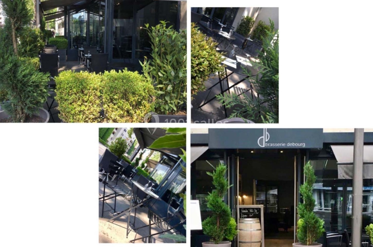 Terrasse et entrée d'une brasserie moderne entourées de végétation, avec mobilier extérieur noir et enseigne visible.