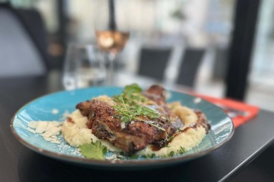 Bouteilles de vin, verres partiellement remplis et plateau de viennoiseries sur une table en bois dans un espace intérieur.